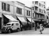 Furgão Ford 1938 estacionado na rua Comendador Afonso Kherlakian, no Centro de São Paulo (SP), tendo o Mercado Municipal ao fundo.