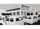 Caminhões Ford com cabine-dupla preparados para a concessionária de energia do Estado do Rio de Janeiro alinhados diante da fábrica da Sidcar; a imagem é de 1992. 